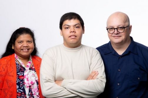 Autistic man standing in the middle of his two parents